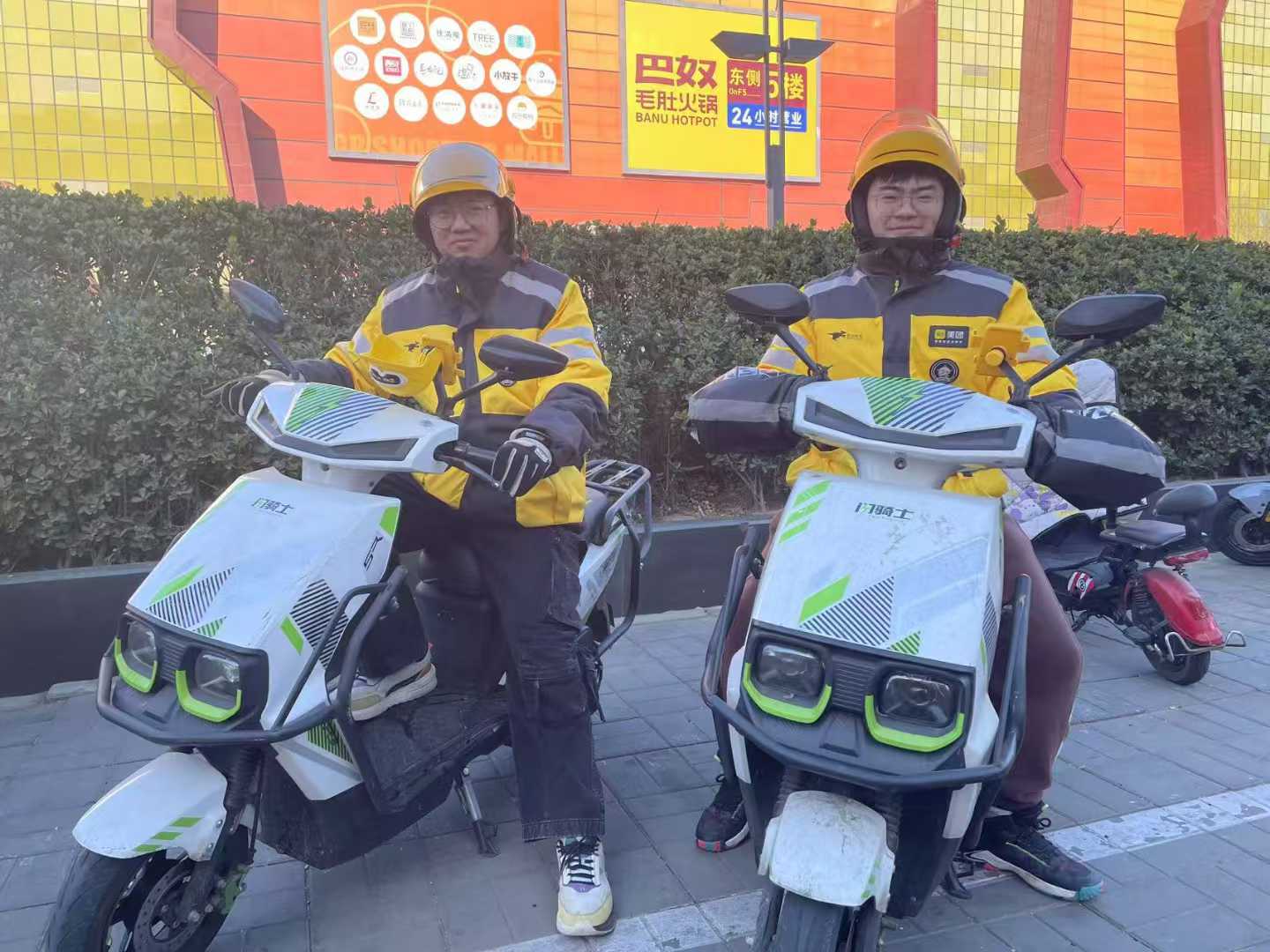 两名外卖骑手与电动车的工作留影
